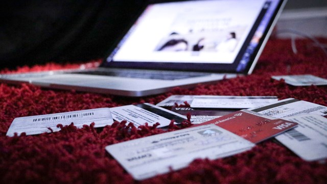 En uppslagen dator och kreditkort utspridda på en röd matta. 