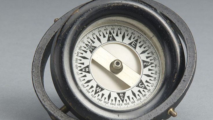 En äldre kompass mot en grå bakgrund.