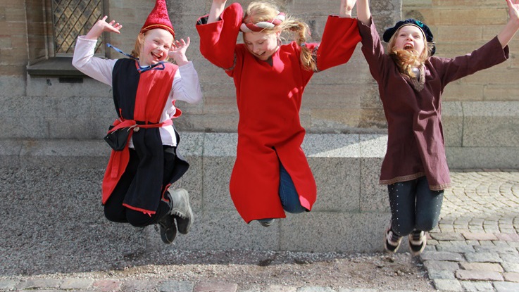 Tre hoppande barn i medeltidskläder