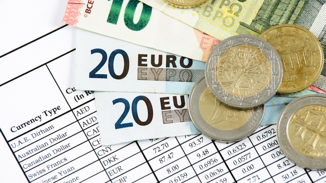 Euro notes and coins placed on a sheet of paper