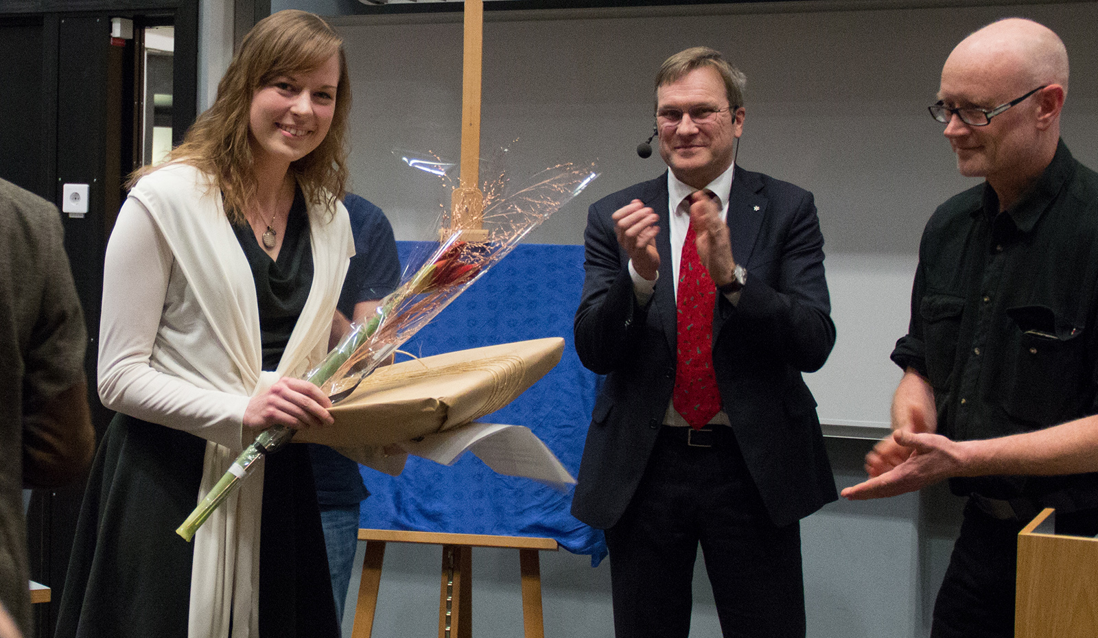 Olivia Landén fick Andreas Rosseaus pris för bästa föreläsning under 2017. Hon applåderas av Dekanus Johan D. Söderholm och Johan Lindgren, som var vän med Andreas Rosseau och en av personerna bakom priset.