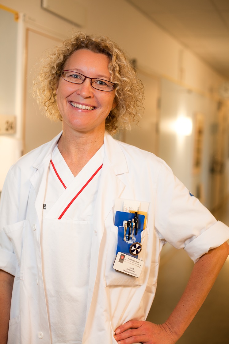Anna Strömberg, forskare i omvårdnad vid LiU, och sjuksköterska, står i sina arbetskläder i en sjukhuskorridor.
