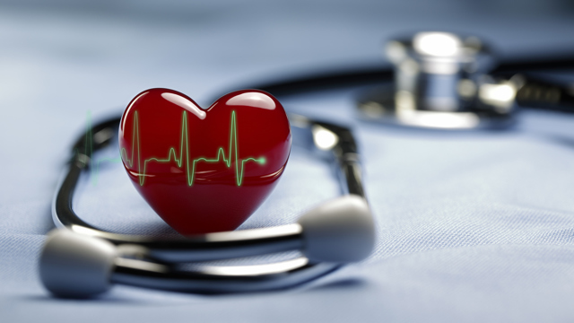 Ett rött hjärta är placerat på en utskrift av en hjärtfrekvens