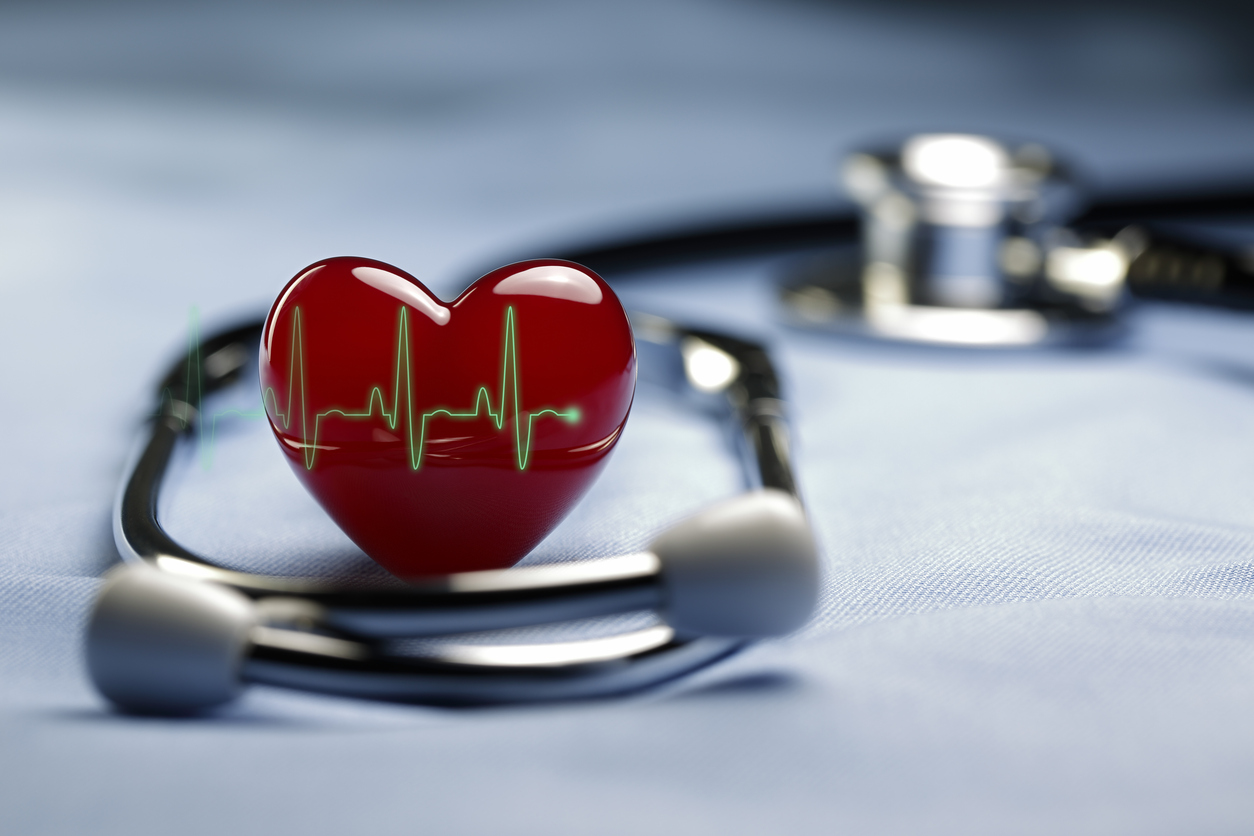 Ett rött hjärta är placerat på en utskrift av en hjärtfrekvens