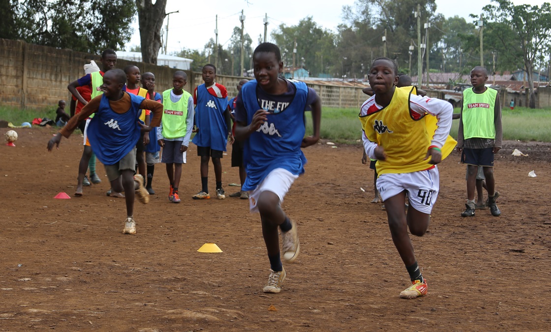Afrikanska barn spelar fotboll.