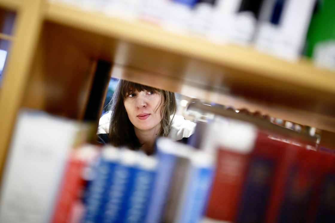 Ung kvinna vid bokhylla