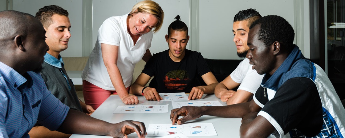 Language training for refugees in a German camp: A female German volunteer is teaching young refugees.