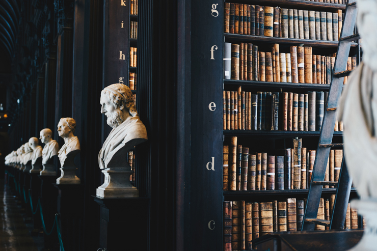 Gammalt bibliotek med statyer och bokhyllor
