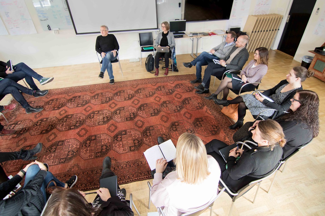 Personer sitter i en cirkel i ett mötesrum.