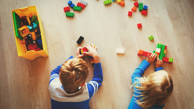 Genrebild från en förskola fär två barn leker med lego på ett golv