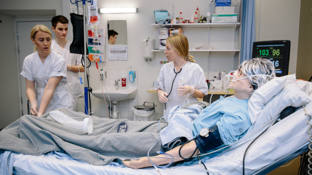 Medicin- och vårdstudenter som övar tillsammans med en simuleringsdocka.