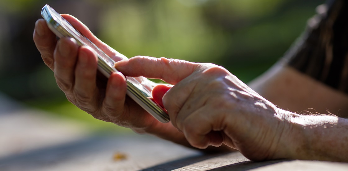 Äldres händer som hanterar smartphone