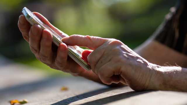Äldres händer som hanterar smartphone