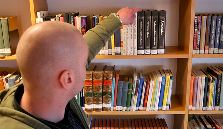 Jim Blomqvist plockar i en bibliotekshylla