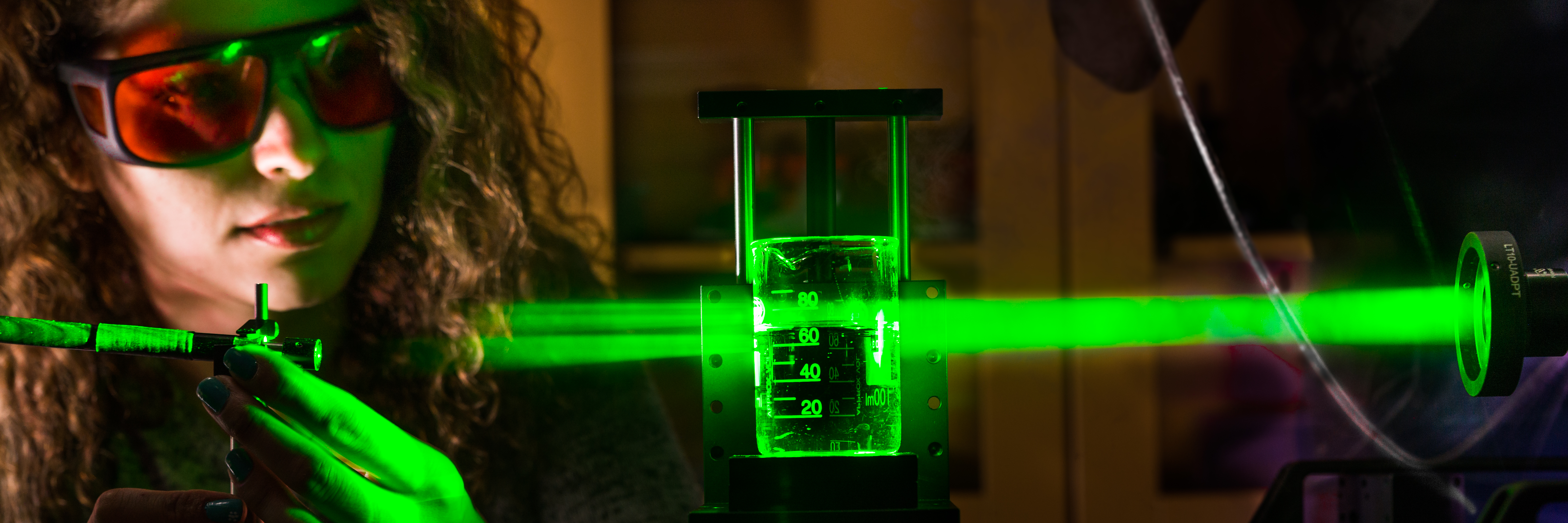 Grön laserstråle i mörker - kvinna med skyddsglasögon