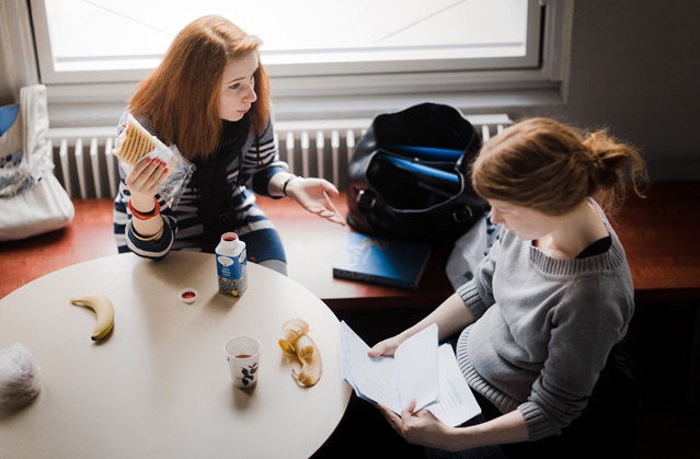Två studenter sitter vid ett bord och pluggar och diskuterar