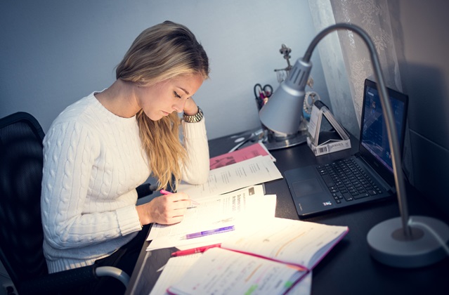 Student sitter vid sitt skrivbord och pluggar