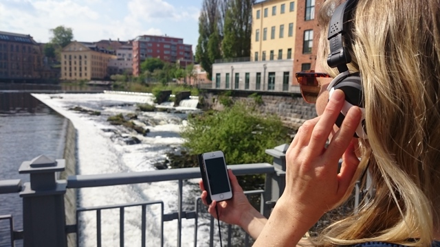 Kvinna med hörlurar och smartphone vid Strömmen