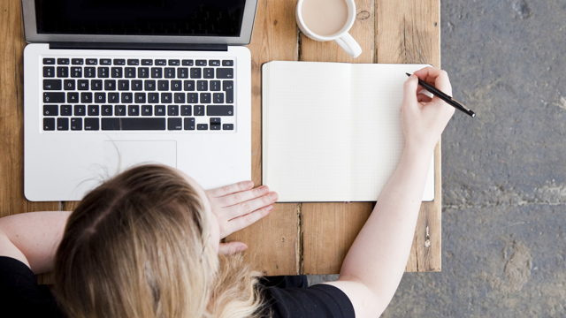 Bild från ovan på en kvinna med en laptop och en notebook / Top view of a woman with laptop and notebook