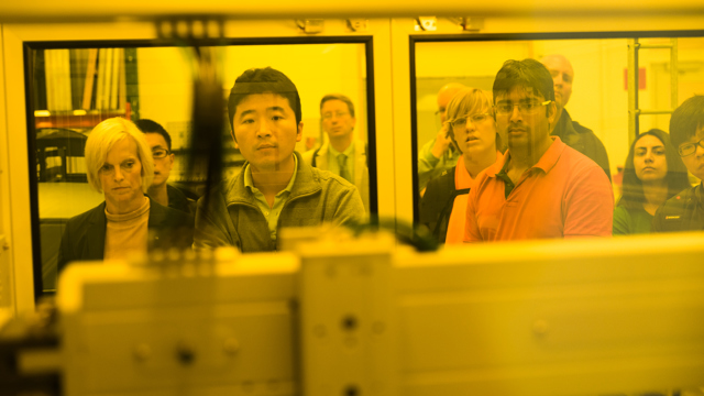 Besökare tittar in i maskin genom gula fönster.