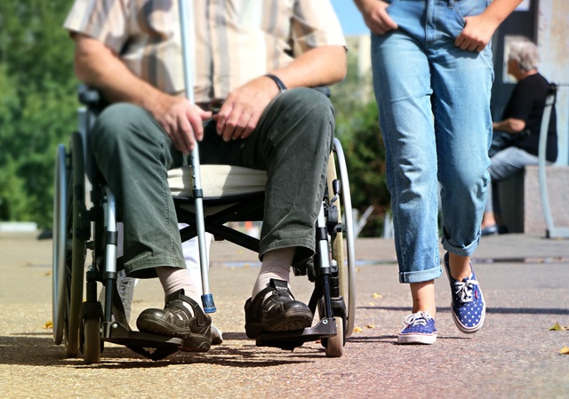Äldre man i rullstol med sällskap