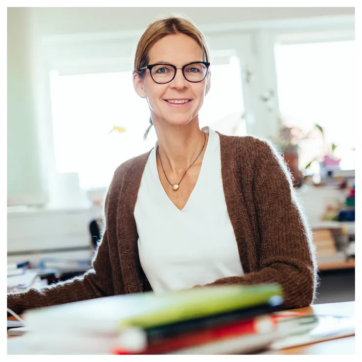 Episode guest Elin Wihlborg is standing in a office and smiles to the camera.