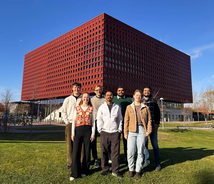 Seven people standing in front of Studenthuset smiling at the camera.