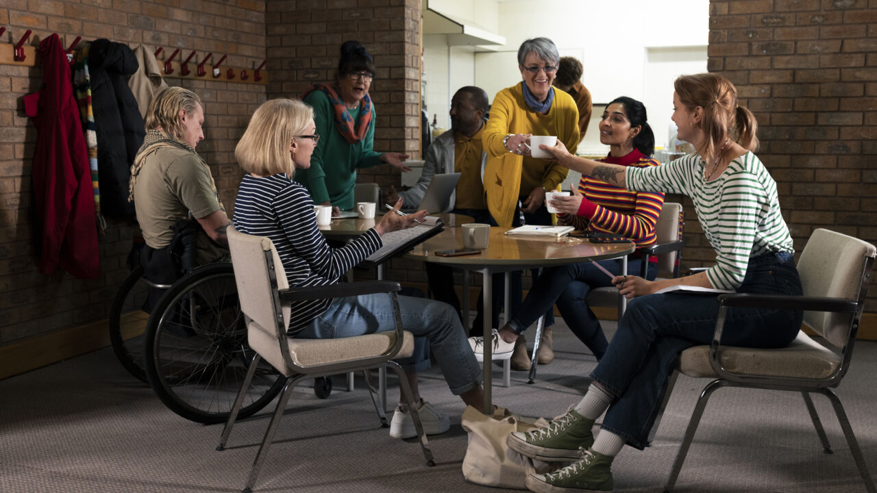 Grupp människor som sitter runt ett bord och pratar.