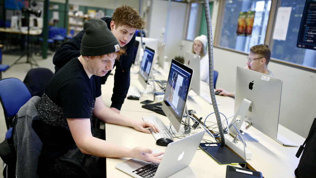 Studenter i sal för programmering, Fascinerade ansiktsuttryck när de betraktar skärmarna.