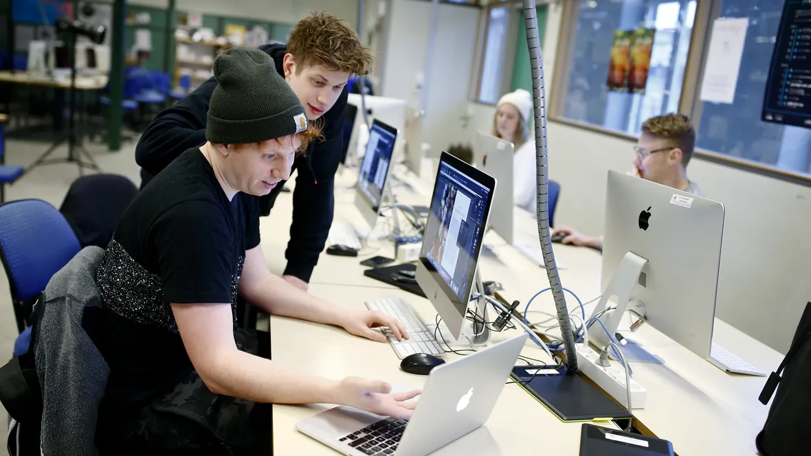 Studenter i sal för programmering, Fascinerade ansiktsuttryck när de betraktar skärmarna.