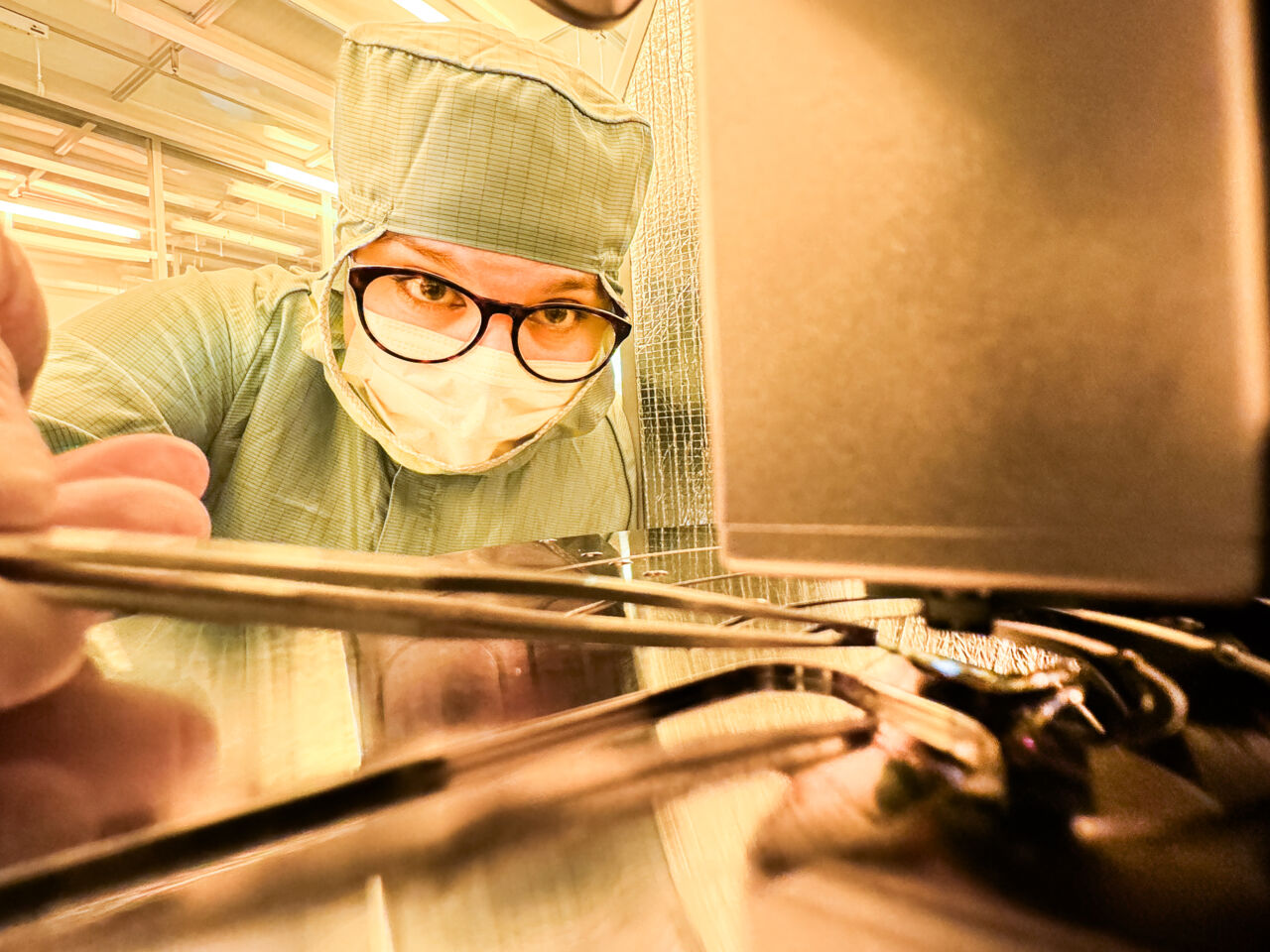 Person i skyddskläder vid ett mikroskop.