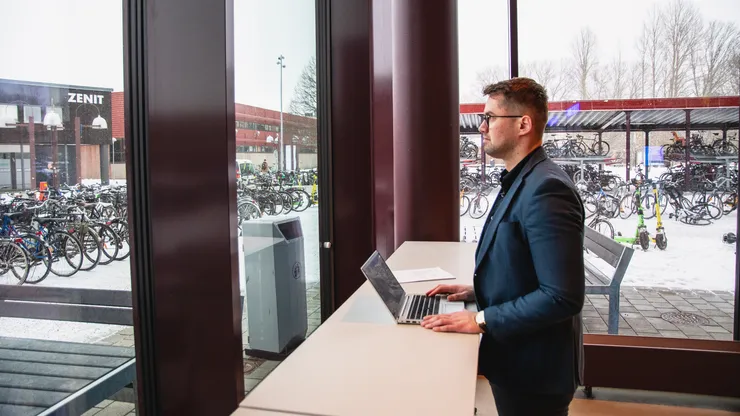 Vlatko Milic står med sin dator och tittar ut genom ett fönster.