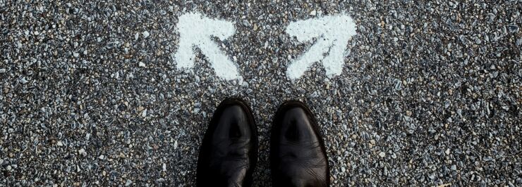 Black shoes on asphalt painted with two white arrows