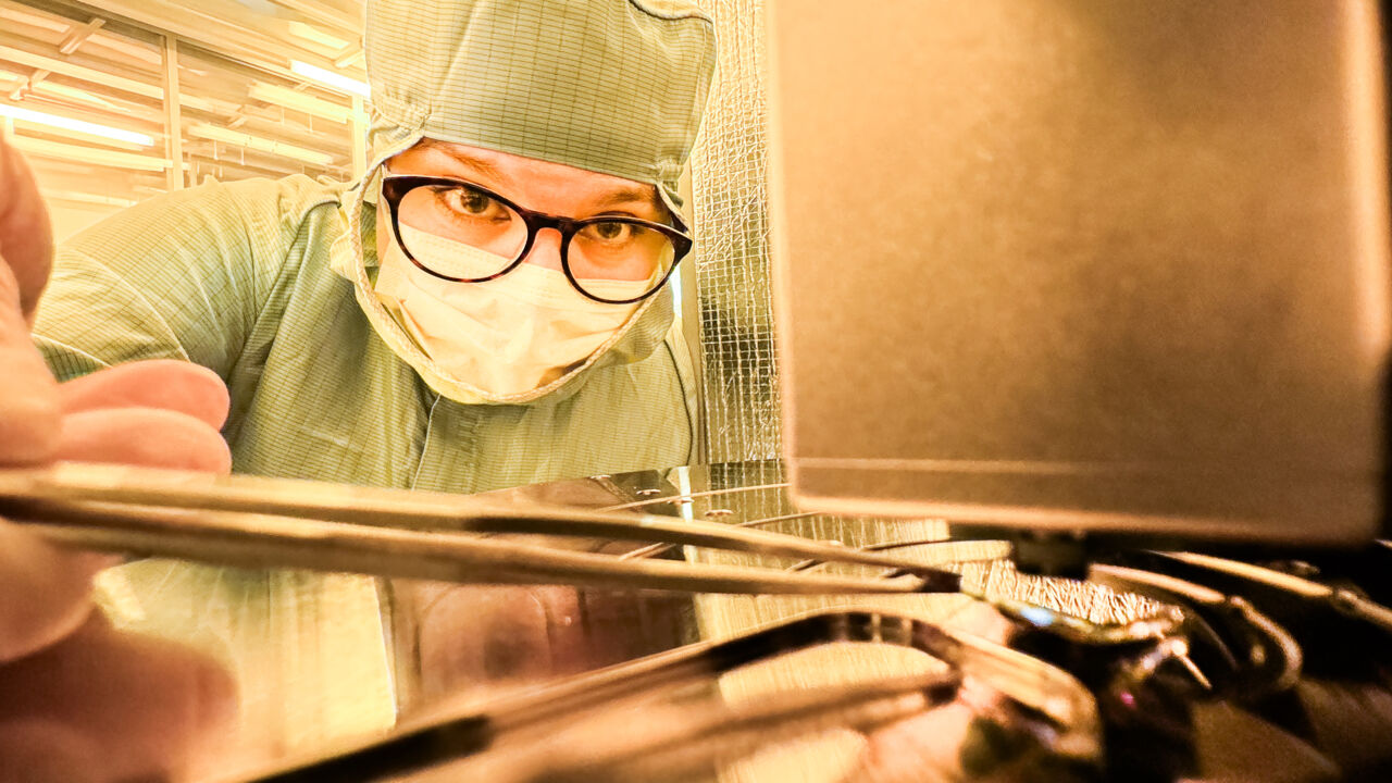 Person in protective gear working with microscope.