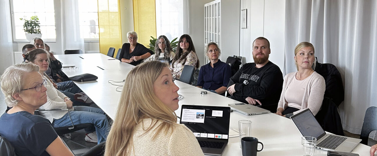 Män och kvinnor sitter runt ett avlångt konferensbord