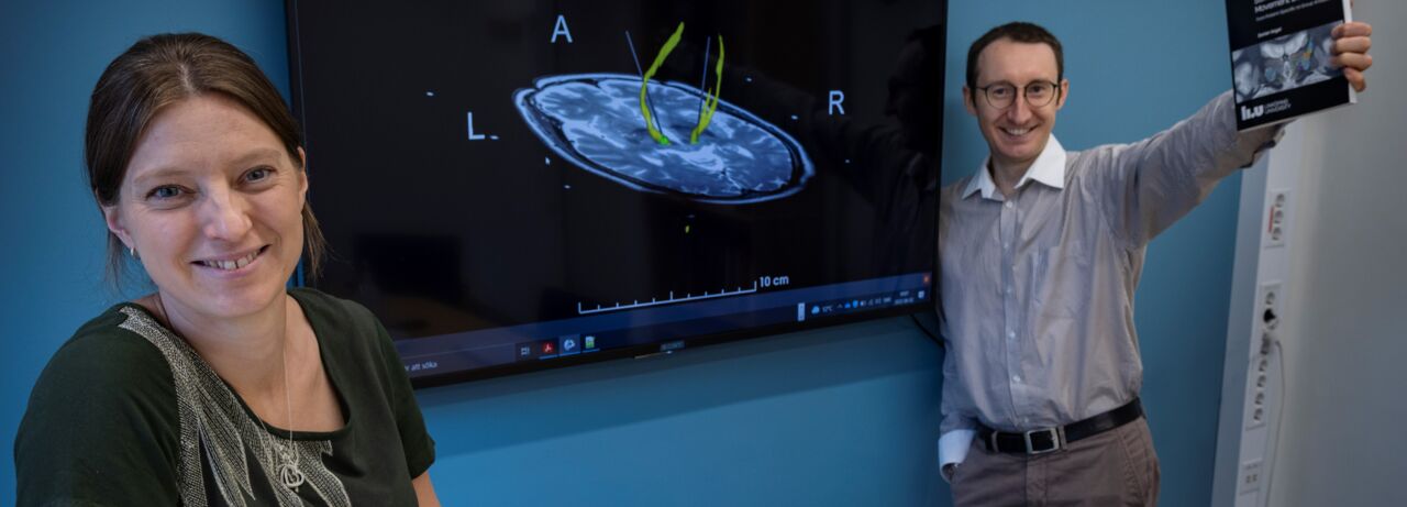 Teresa Nordin and Dorian Vogel in front of a TV screen with an MRI image.