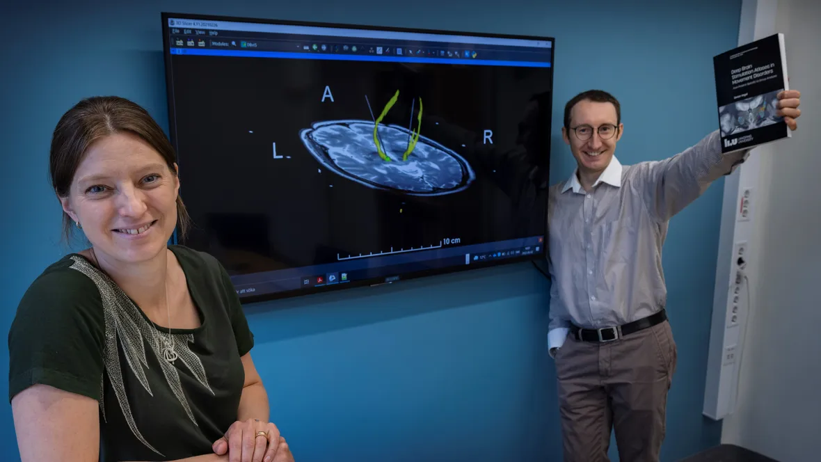 Teresa Nordin and Dorian Vogel in front of a TV screen with an MRI image.