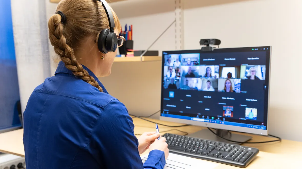 Kvinna sitter i digitalt möte framför en datorskärm.