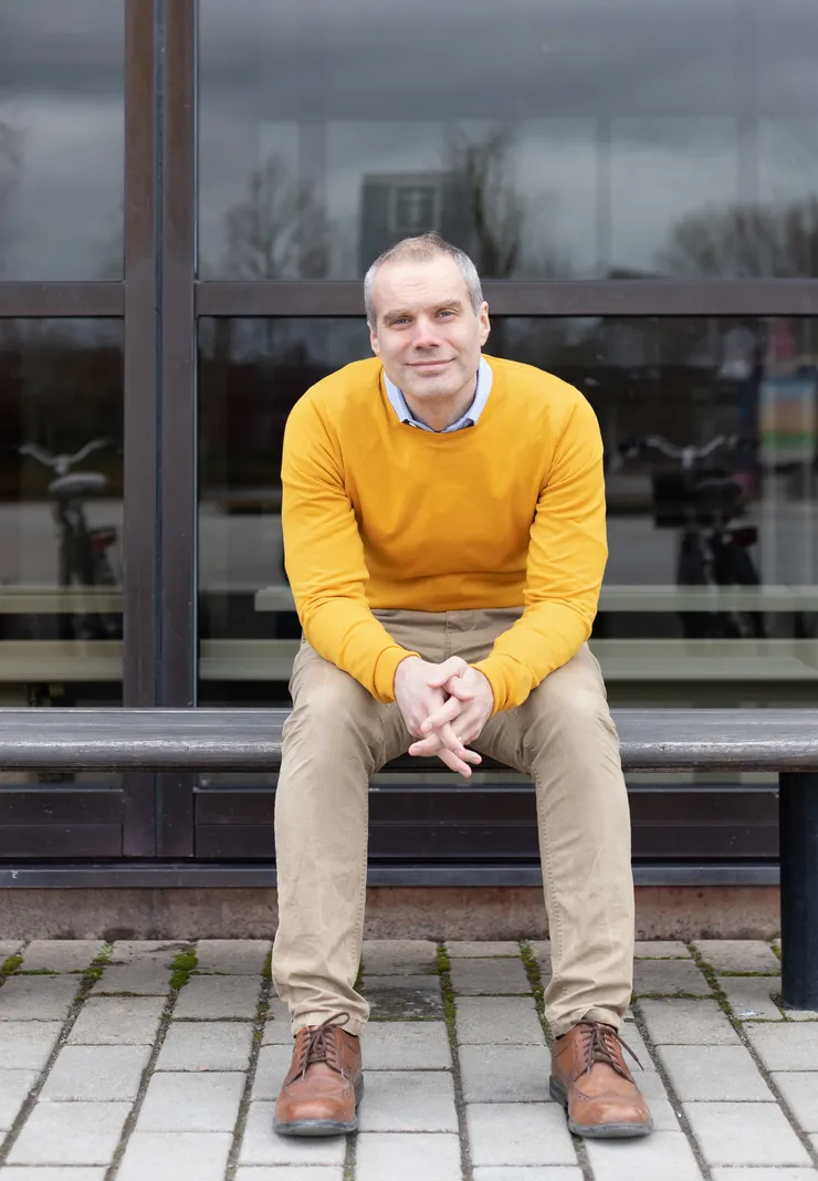 Erik Sandberg sitter på en bänk framför en byggnad