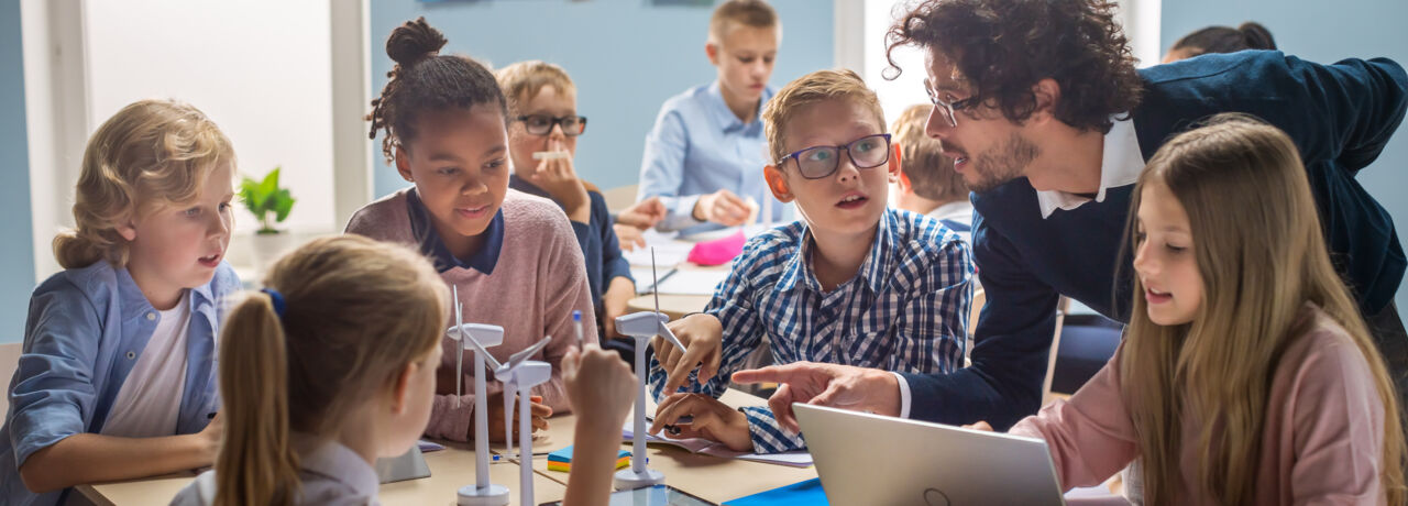 A teacher teaching some younger students about technology.