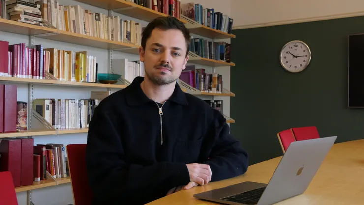 Thomas Keating sitter med datorn framför sig på ett bord.