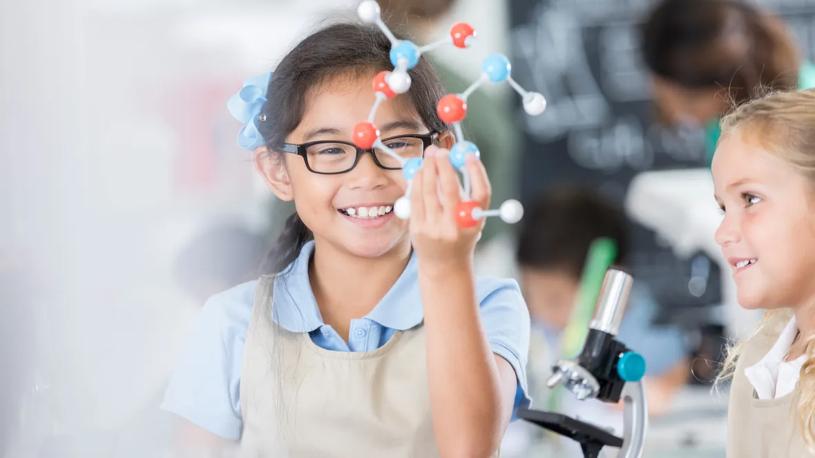 A happy girl holding up a colecular model.