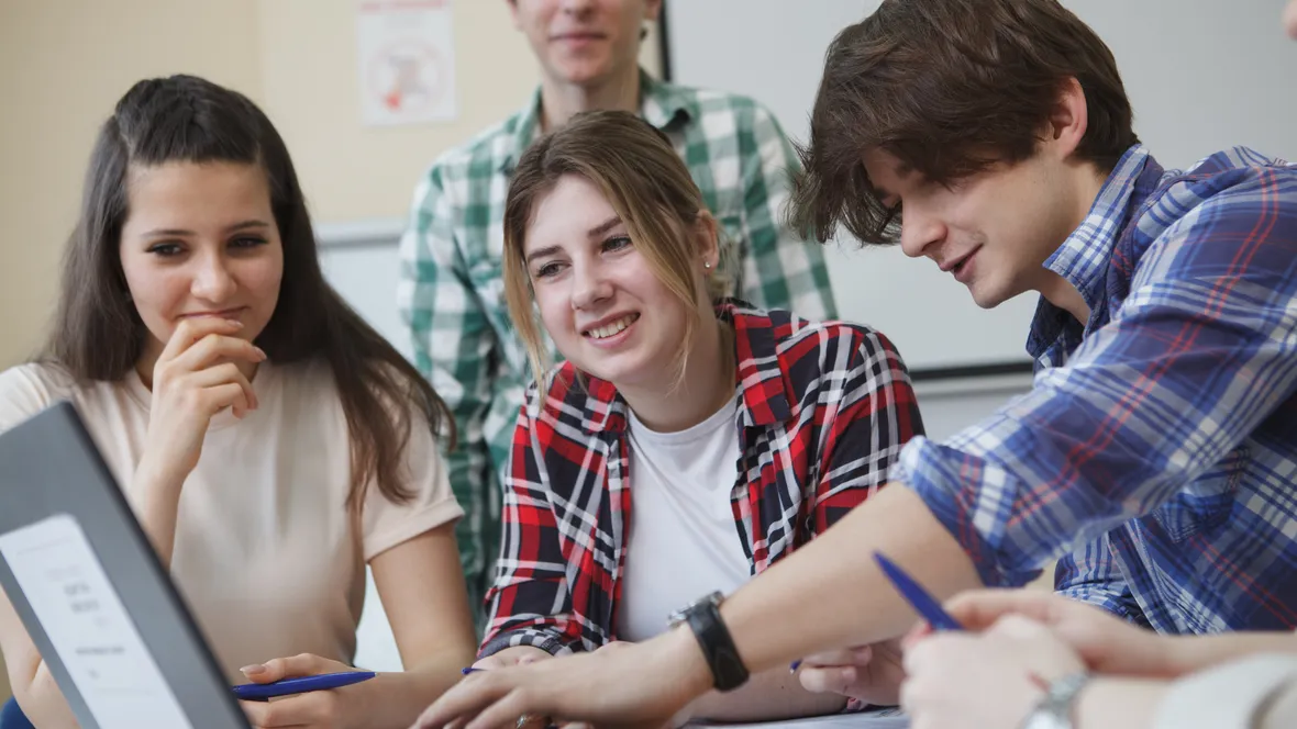 A group of students sitting at a compuer discussing.