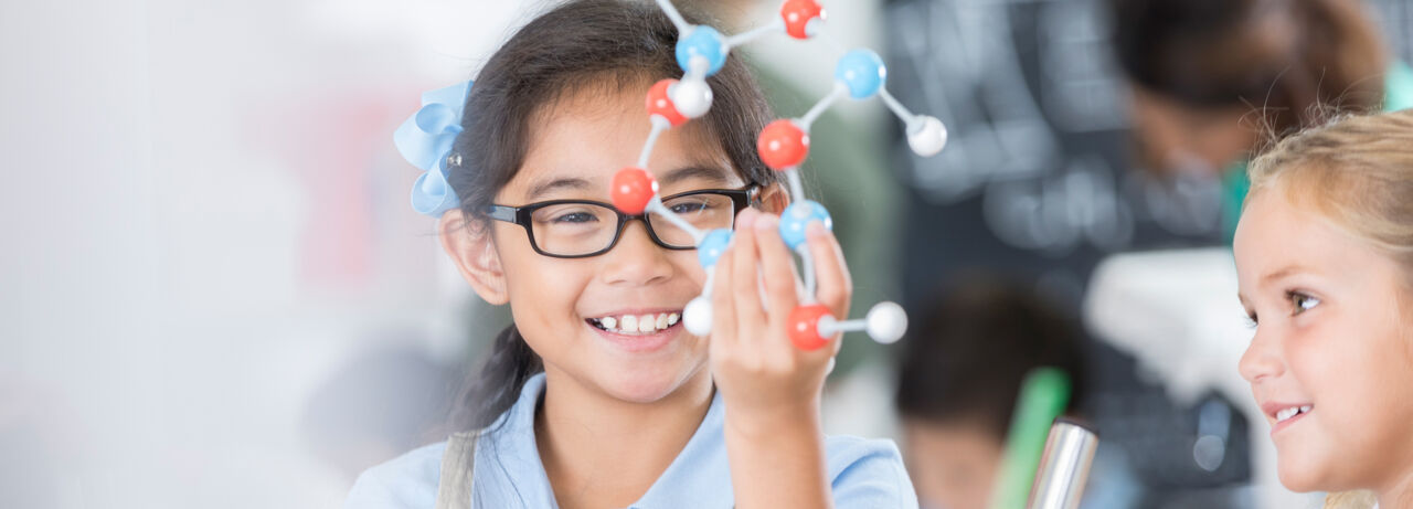A happy girl holding up a colecular model.