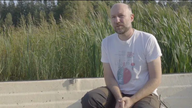 A man sitting in front of tall grass