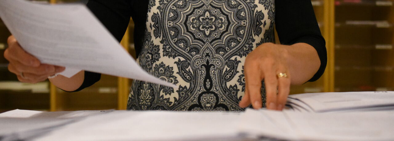 En person sorterar papershögar.