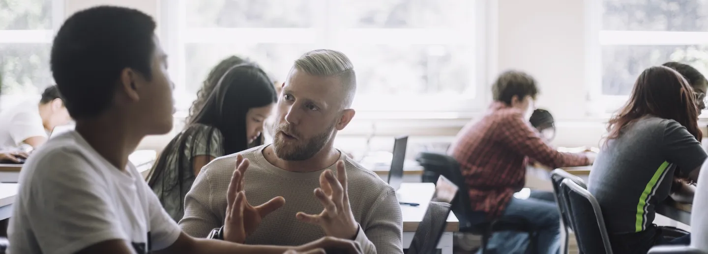 Lärare förklarar för elev i ett klassrum.