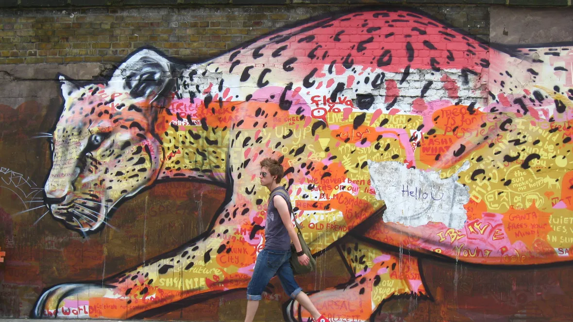 Person som går framför en stor väggmålning föreställande en leopard.