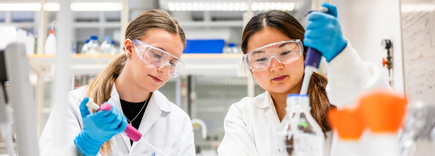 Två studenter labbar.