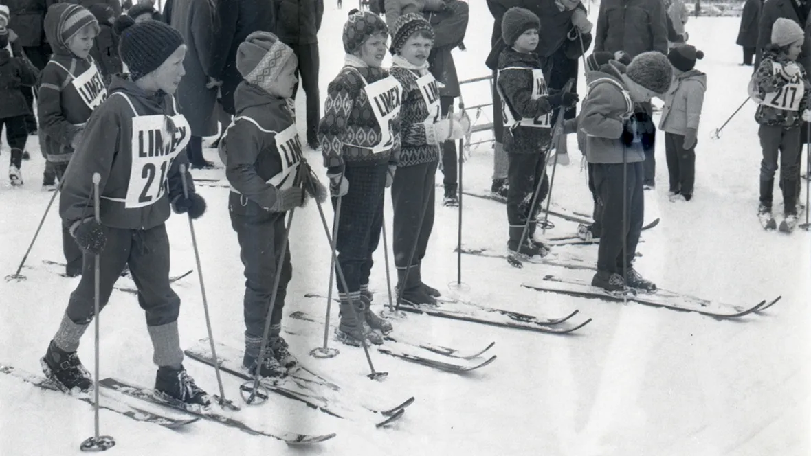 Svartvit bild på barn som ska åka skidor.